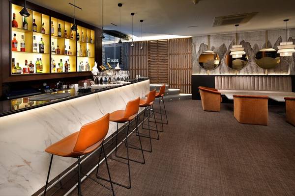 Barbereich des HCC St. Moritz Hotels mit Marmortheke und braunen Stühlen.
