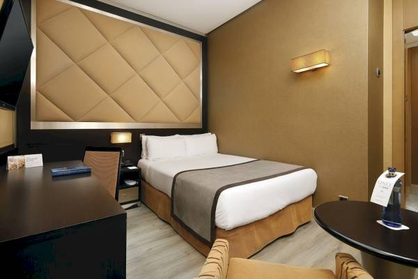 Innenansicht eines Hotelzimmers im HCC St. Moritz mit Bett, Schreibtisch und Nachttisch.