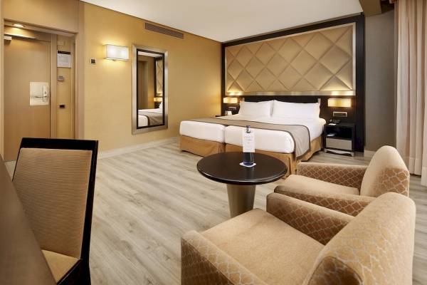 Hotelzimmer im HCC St. Moritz mit Doppelbett, Tisch, Stühlen und Spiegel.