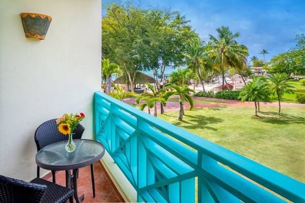 Blick vom Balkon des Hilton La Romana auf eine Rasenfläche und Palmen