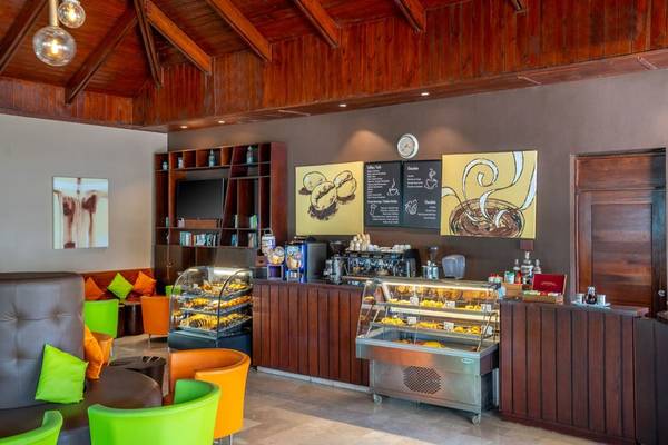 Cafébereich im Hilton La Romana mit Holzmöbeln, bunten Stühlen und Kuchentheke.