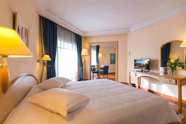 Ein modernes Hotelzimmer mit einem großen Bett, Fernseher und einem Schreibtisch im Hintergrund.