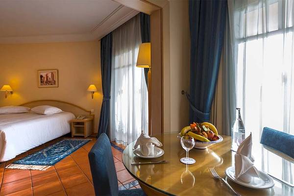 Innenansicht eines Hotelzimmers im Medina Belisaire mit Bett, Tisch und Fenstern.