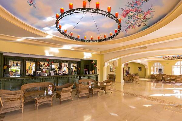 Lobby des Medina Belisaire & Thalasso Hotels mit einer gemusterten Decke, einer Theke und Rattanmöbeln.