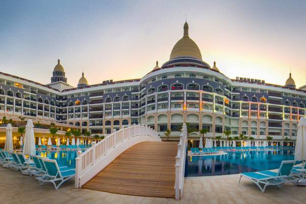 Außenansicht des Diamond Premium Hotel & Spa mit Brücke über dem Pool und Lounge-Stühlen