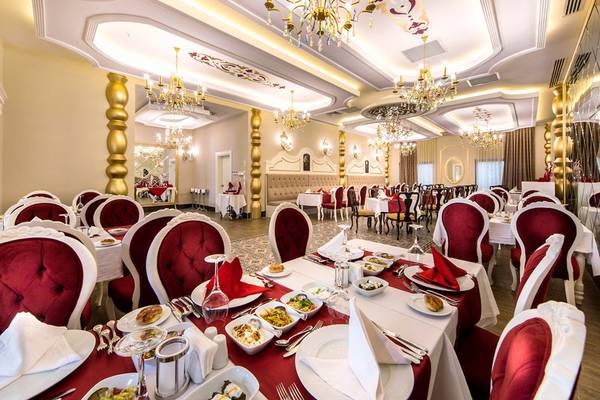 Restaurant im Diamond Premium Hotel & Spa mit eleganten roten Stühlen und goldenen Kronleuchtern.