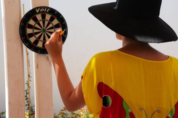 Eine Person in einem gelben T-Shirt wirft einen Dart auf ein Zielbrett.