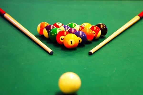 Ein Pooltisch mit bunten Kugeln und Stöcken, die Kugel Nummer 1 ist hervorgehoben.