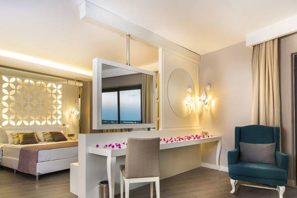 Innenansicht eines Zimmers im Diamond Premium Hotel & Spa mit Bett, Schreibtisch, Stuhl und Blick auf den Ozean.