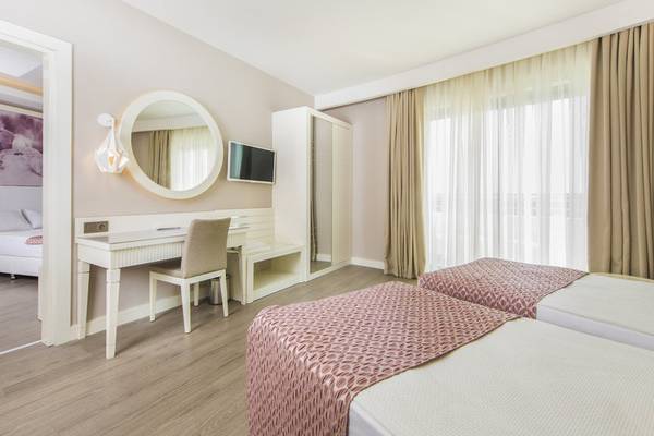Innenansicht eines Doppelzimmers im Diamond Premium Hotel & Spa mit zwei Betten, Schreibtisch und Spiegel.
