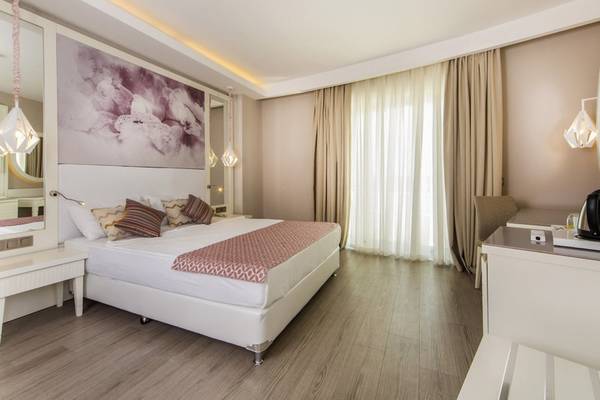 Innenansicht des Schlafzimmers im Diamond Premium Hotel mit einem großen Bett, Dekor und Möbeln.