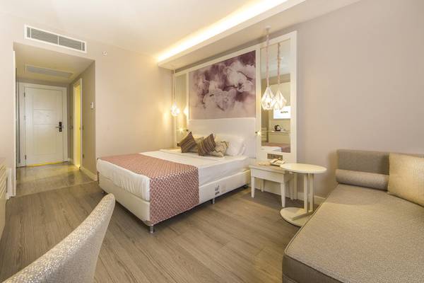 Das moderne Schlafzimmer im Diamond Premium Hotel & Spa mit einem großen Bett, einem Nachttisch und einer gemütlichen Sitzecke.