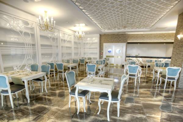 Innenbereich des Azura Deluxe Resort & Spa Restaurants mit weißen Tischen und Stühlen.