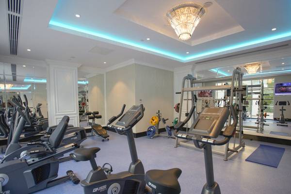 Fitnessstudio im Azura Deluxe Resort & Spa mit Cardiogeräten und blauem Teppich.