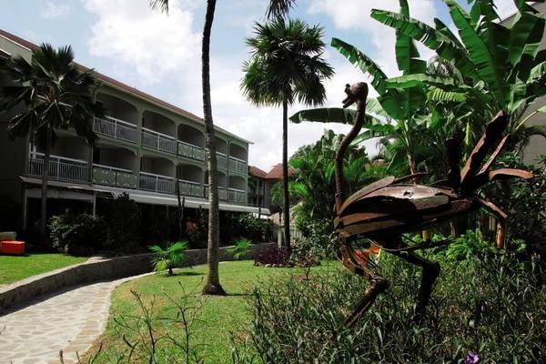 Außenansicht des La Pagerie - Tropical Garden Hotel mit gepflegtem Garten und Flamingoskulptur.