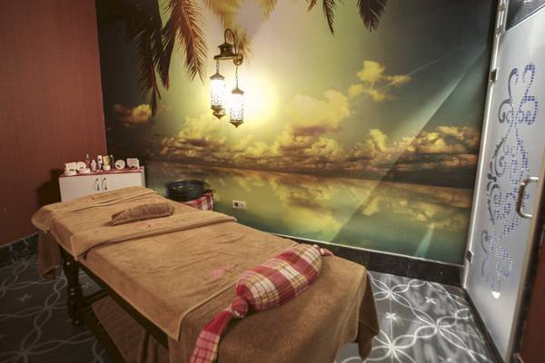 Behandlungsraum im Azura Deluxe Resort & Spa mit tropischem Wandbild und Massageliege.