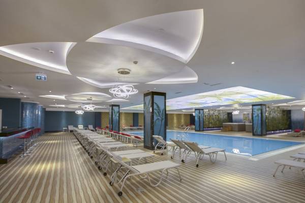 Innenpoolbereich des Azura Deluxe Resort & Spa mit Liegestühlen und blauer Wandgestaltung