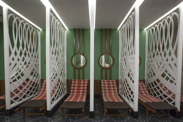 Innenbereich der Saunalounge im Azura Deluxe Resort & Spa mit roten und weißen Sitzbänken, weißen Gitterwänden und grünen Wänden.
