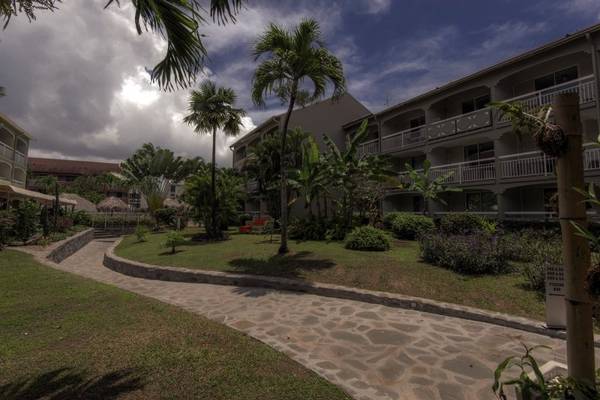 Außenbereich des La Pagerie - Tropical Garden Hotel mit gepflastertem Weg und grüner Landschaft.