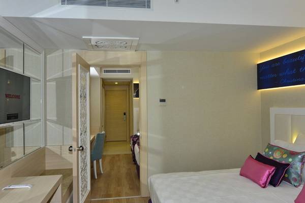 Innenansicht eines Zimmers im Azura Deluxe Resort & Spa mit Bett, Schreibtisch und Fernseher.