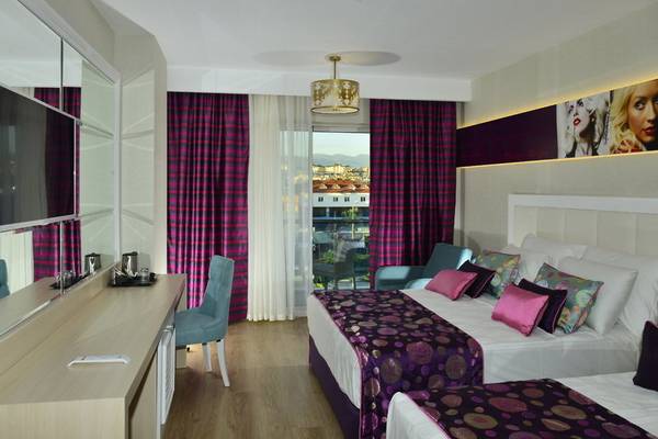 Innenansicht eines Zimmers im Azura Deluxe Resort & Spa mit zwei Betten, Möbeln und einem Balkon.