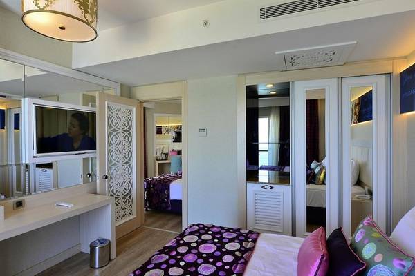 Schlafzimmer im Azura Deluxe Resort & Spa mit großem Bett, Fernseher, Spiegel und Dekor.