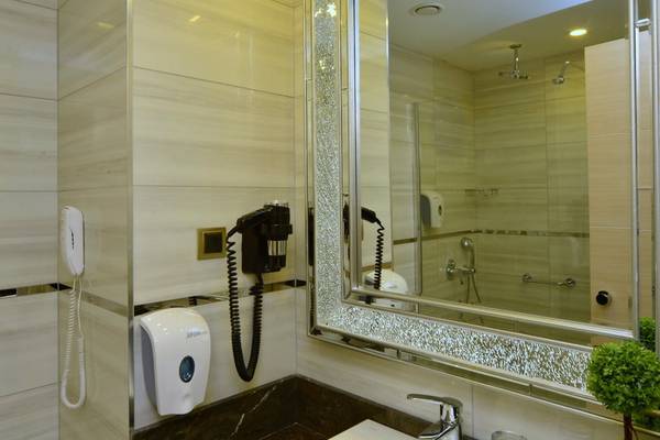 Badezimmer im Azura Deluxe Resort & Spa mit Spiegel, Föhn, Seifenspender und Waschbecken.