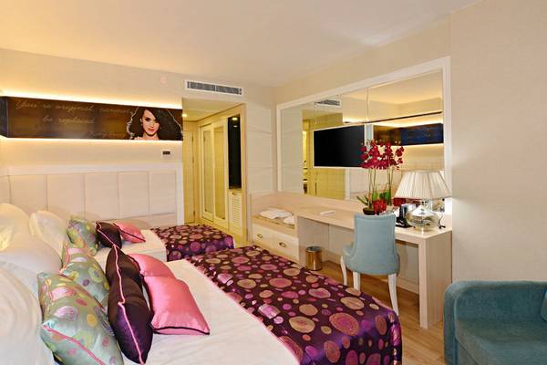 Doppelzimmer im Azura Deluxe Resort & Spa mit zwei Betten, Schreibtisch und großem Spiegel.