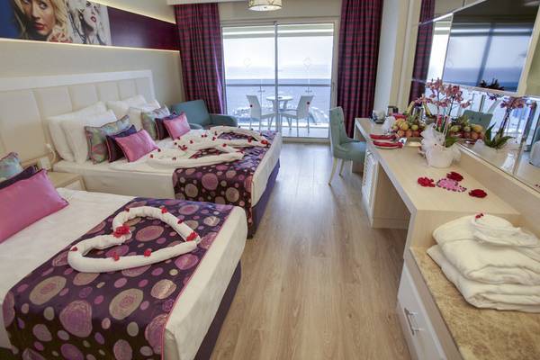 Doppelzimmer im Azura Deluxe Resort & Spa mit Meerblick, zwei Betten mit Blumendekoration, Balkon mit Tisch und Stühlen.