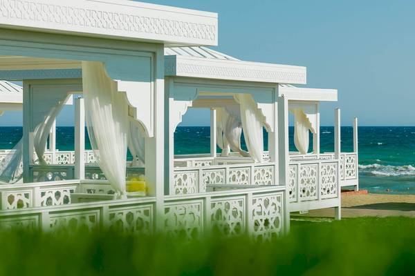 Ein Bild von weißen Pavillons mit strukturierten Vorhängen am Strand des Güral Premier Belek Hotels.