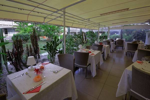 Foto von La Pagerie - Tropical Garden Hotel Restaurant mit Tischen und Stühlen unter einer überdachten Terrasse.