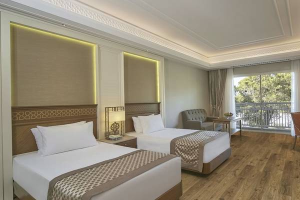 Doppelzimmer im Güral Premier Belek Hotel mit zwei Betten, Schreibtisch, Sessel, und Balkon.