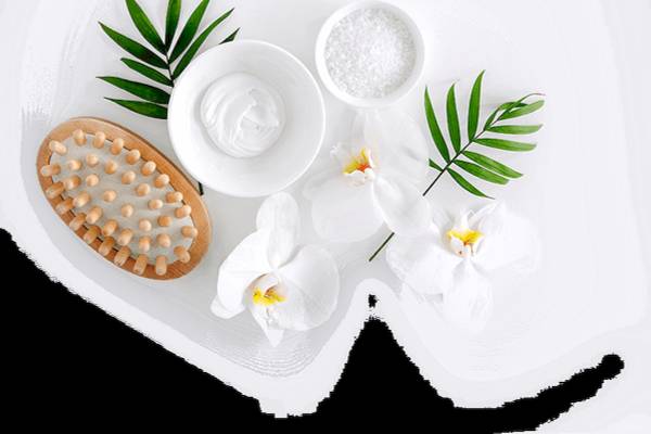 Gesichtspflegeprodukte wie eine Creme, Salz und Blüten auf weißem Hintergrund