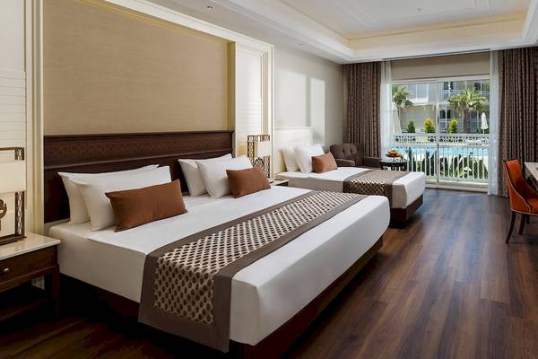 Hotelzimmer im Güral Premier Belek mit zwei Betten, einem Schreibtisch und einem Balkon mit Poolblick.