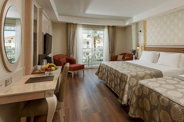 Hotelzimmer im Güral Premier Belek mit zwei Betten, Schreibtisch, Stühlen und Balkon.