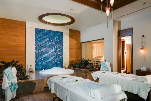 Spa-Bereich im Güral Premier Belek Hotel mit zwei Massagetischen und einem Whirlpool.