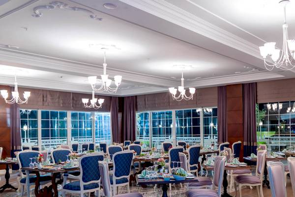 Restaurant im Güral Premier Belek Hotel mit blauen Stühlen und Tischdecken.