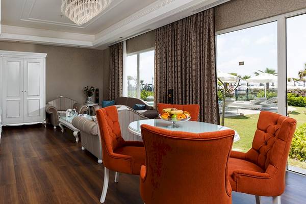 Innenansicht der Suite im Güral Premier Belek Hotel mit Esstisch, Sofas und Ausblick auf den Garten.