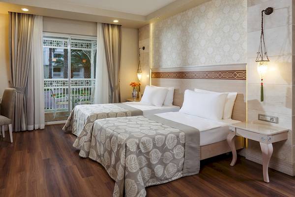 Hotelzimmer im Güral Premier Belek mit zwei Betten, einem Schreibtisch und einem Balkon.