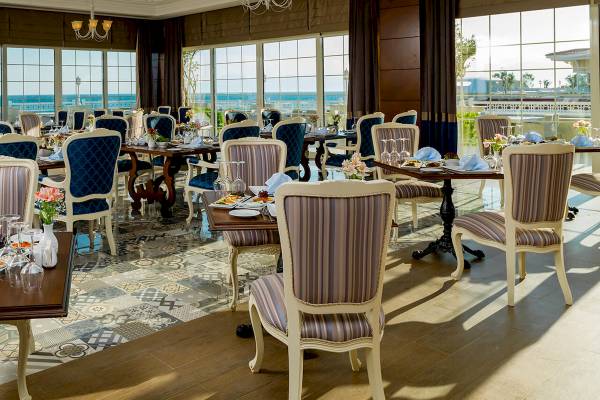 Hotelrestaurant mit Blick auf das Meer und blauen Stühlen.