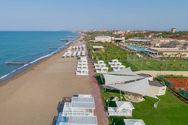 Luftaufnahme des Güral Premier Belek mit Strand, weißen Pavillons und Meer