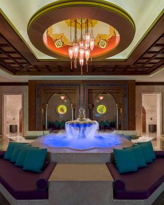 Hotellobby des Güral Premier Belek mit einem zentralen Wasserbrunnen und einer großen hängenden Lampe.