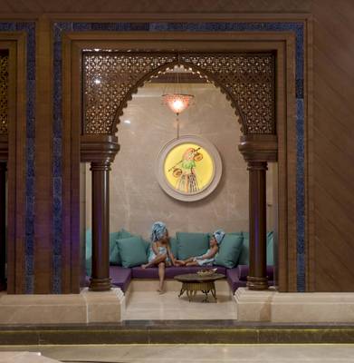 Zwei Frauen sitzen in einem Loungebereich des Güral Premier Belek Hotels, umgeben von stilvollen Möbeln und Wandkunst.