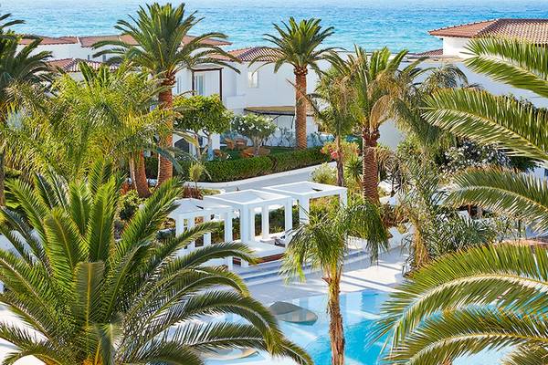 Aussenansicht des Grecotel Caramel Boutique Resorts mit Swimmingpool und Palmen