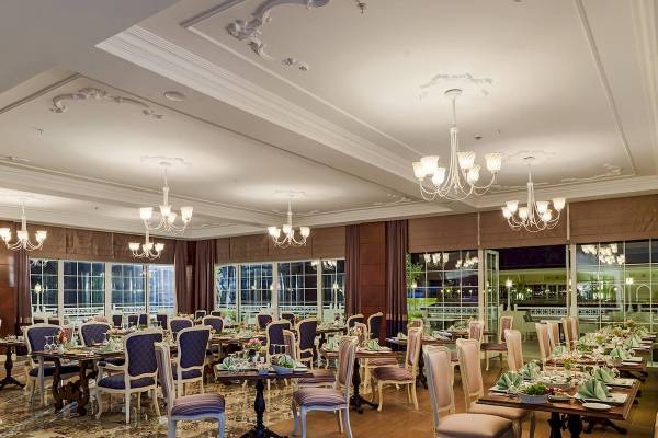 Innenansicht des Restaurants im Güral Premier Belek Hotel mit eleganten Tischen und Stühlen.