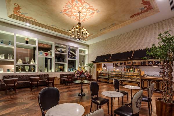 Innenbereich des Rubi Platinum Spa Resort & Suites mit Holzboden, runden Tischen, Stühlen und einer großen Deckenleuchte.