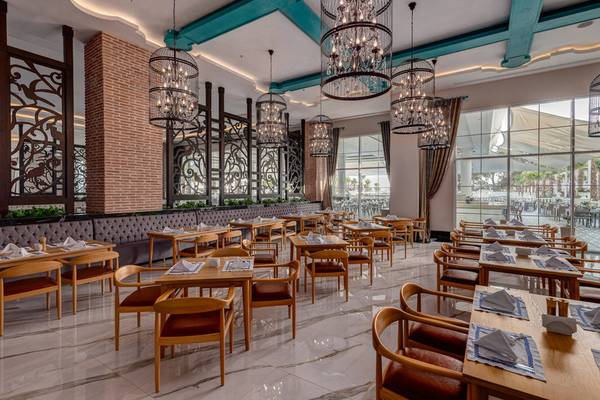 Innenansicht des Restaurants im Rubi Platinum Spa Resort & Suites mit vielen Holztischen und Stühlen.