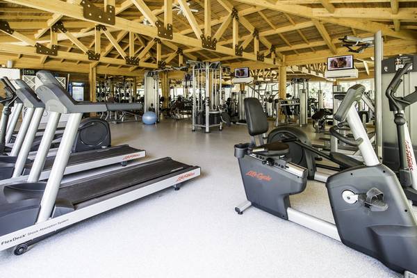 Fitnessstudio im Rubi Platinum Spa Resort & Suites mit Holzdecke, Laufbändern und Fitnessgeräten.