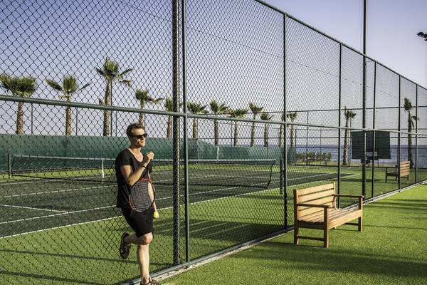 Ein Mann mit Tennisschläger und Ball steht an einem Tennisplatz im Rubi Platinum Spa Resort.