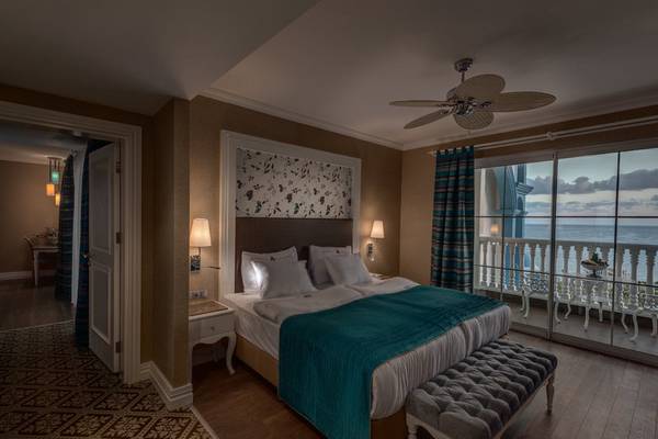 Schlafzimmer mit Bett, Nachttisch, Deckenventilator und Meerblick